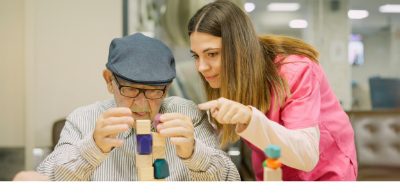 A man building blocks with help from a female carer
