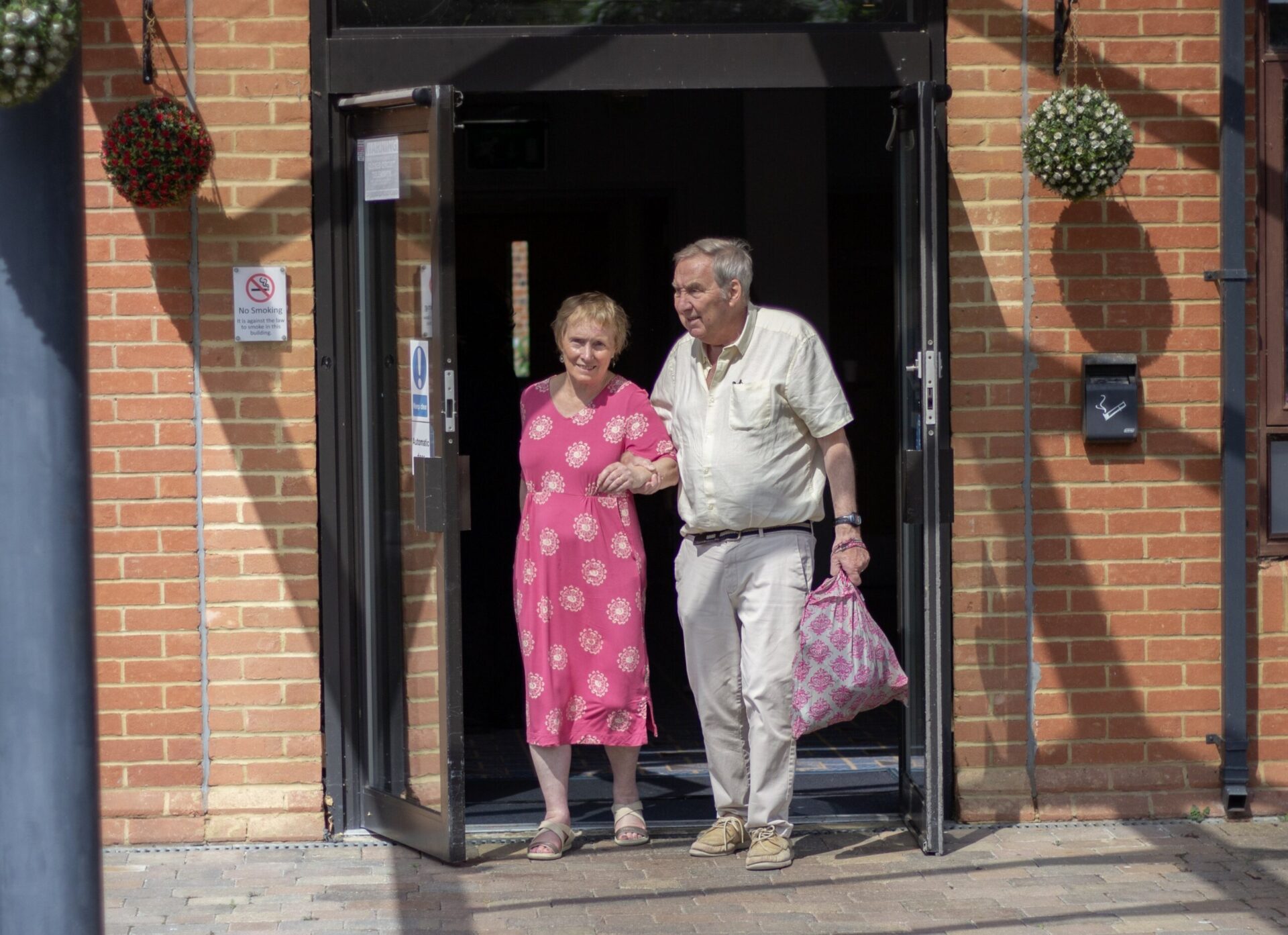 A male carer supporting his wife as they leave a venue